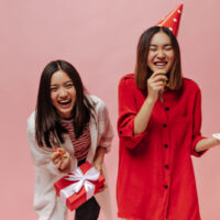zwei Geburtstagsmädchen lachen mit Kuchen und Luftballons