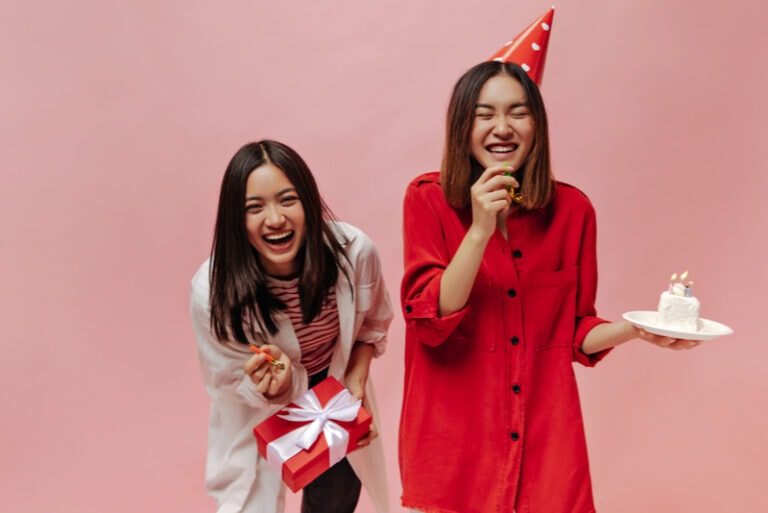 zwei Geburtstagsmädchen lachen mit Kuchen und Luftballons