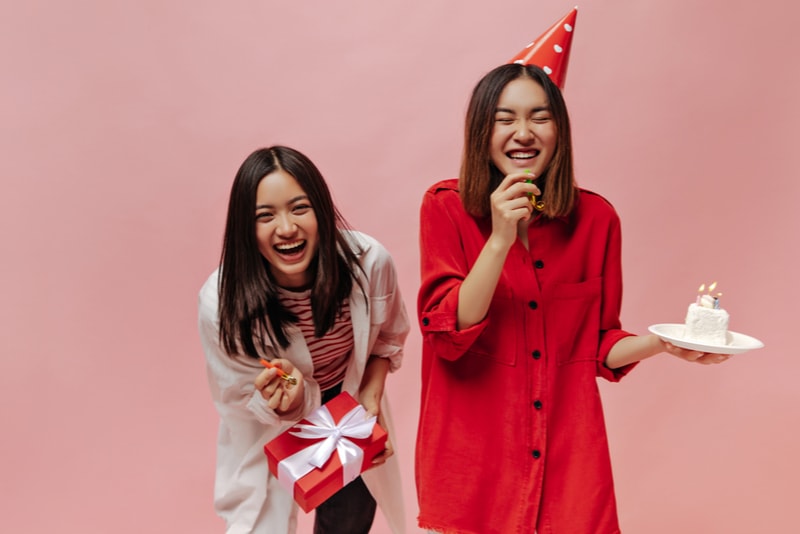 zwei Geburtstagsmädchen lachen mit Kuchen und Luftballons