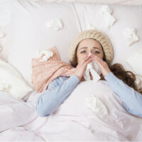 Kranke Frau, die mit hohem Fieber im Bett liegt