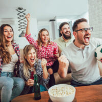 Fröhliche Freunde oder Fußballfans, die Fußball im Fernsehen sehen