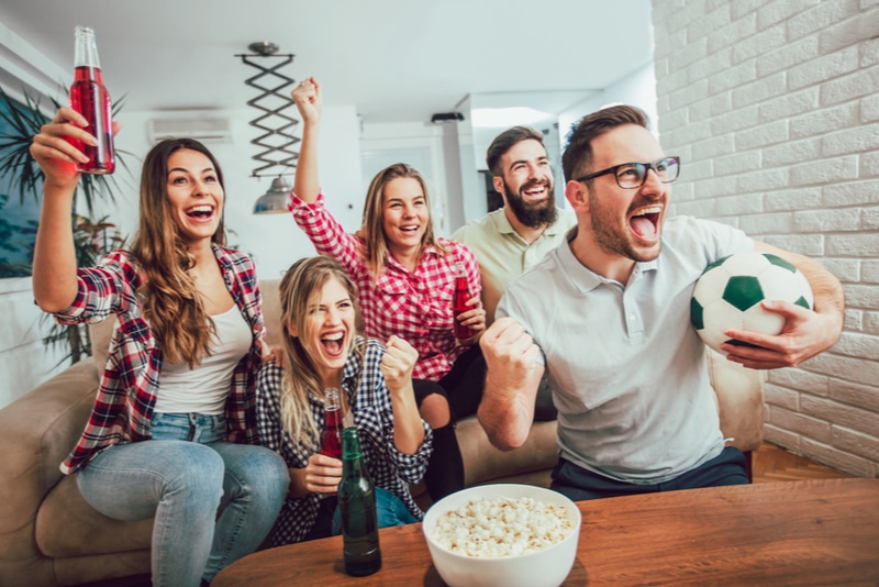 Fröhliche Freunde oder Fußballfans, die Fußball im Fernsehen sehen