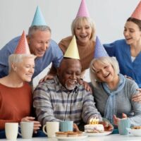 an elderly man celebrates his birthday with his colleagues