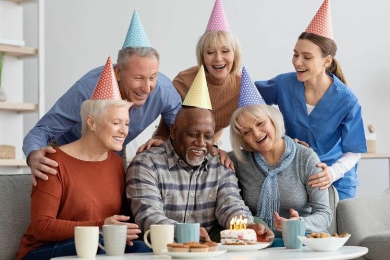 an elderly man celebrates his birthday with his colleagues