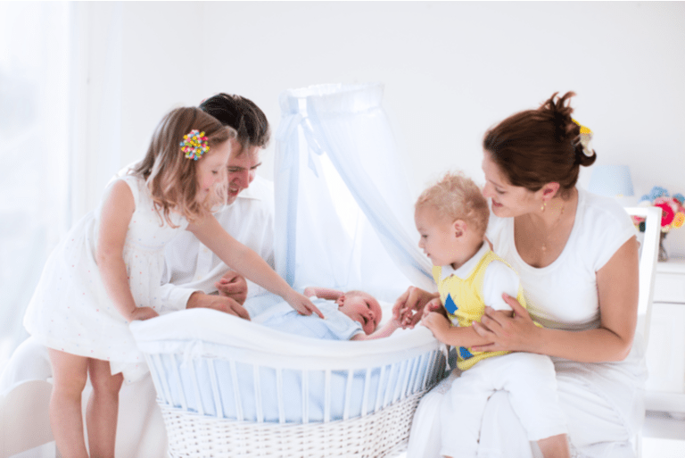 Große Familie mit drei Kindern im weißen Schlafzimmer