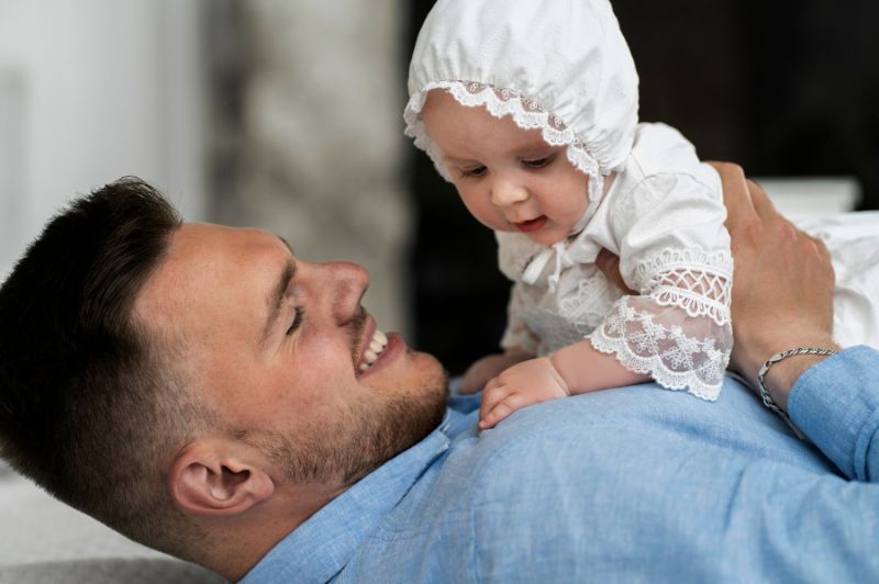 vater hält sein baby bei der taufzeremonie