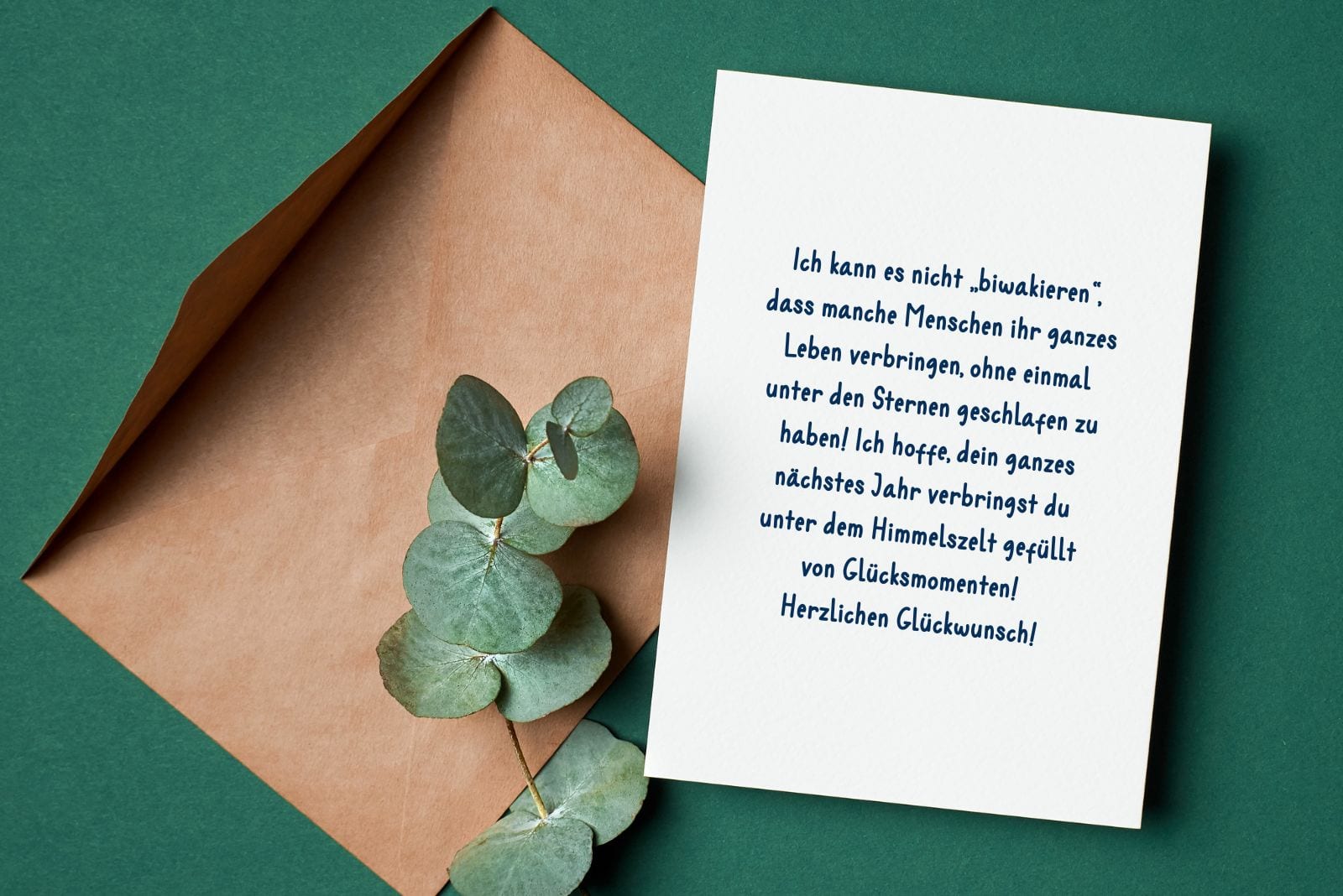 dekorative Blätter, grüner Umschlag und eine Karte mit einem schönen Geburtstagswunsch für einen Camper