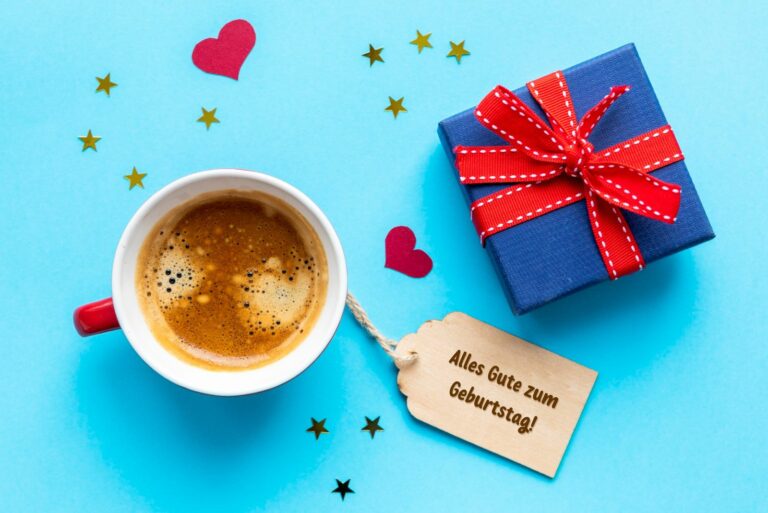 Geburtstagsgeschenk und eine Tasse Kaffee mit einer "Happy Birthday"-Notiz auf dem Tisch