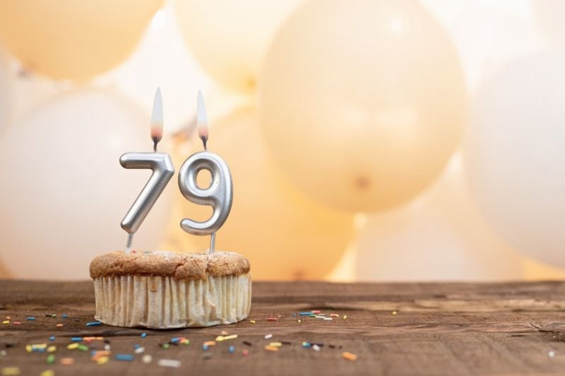 Kerze Nummer 79 in einem Cupcake vor dem Hintergrund von Luftballons.